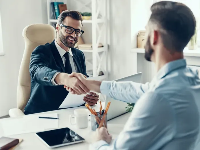 Professional handshake between businessman in suit and client across desk in Town Directory List